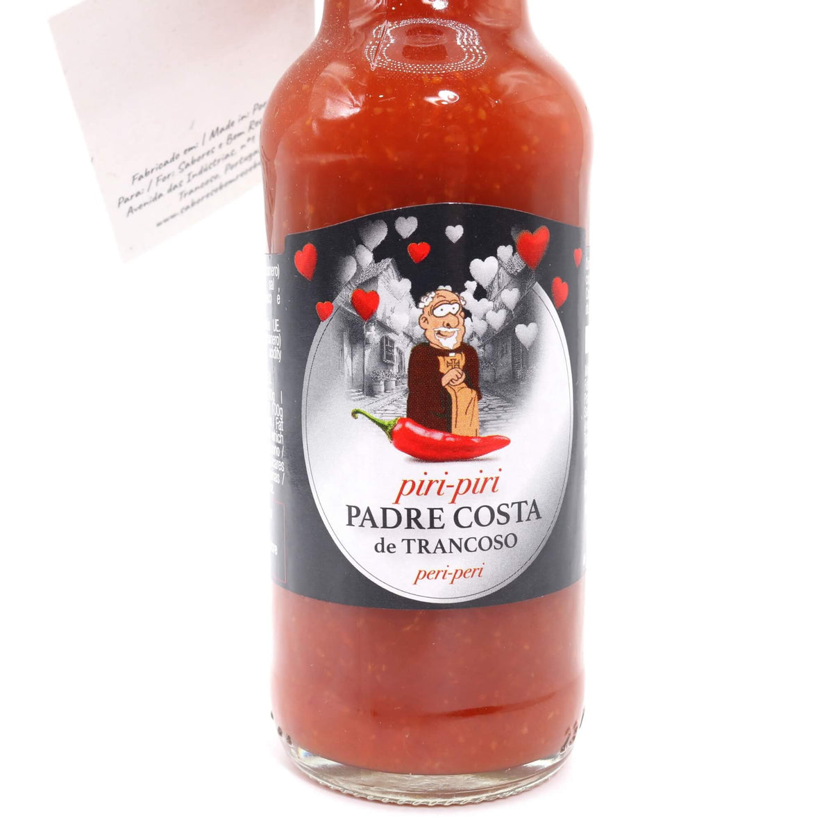 A glass bottle of Padre Costa de Trancoso piri-piri hot sauce with a black and white label featuring a cartoon character and red hearts, filled with red sauce, on a white background.