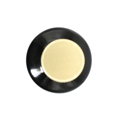 A circular black object with a textured, brushed gold center, photographed from directly above on a solid white background.