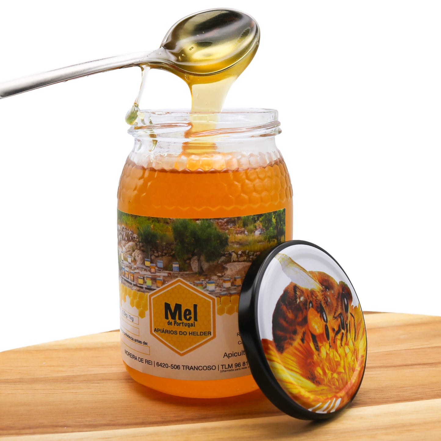 Jar of honey with a spoon dripping honey, on a wooden surface.