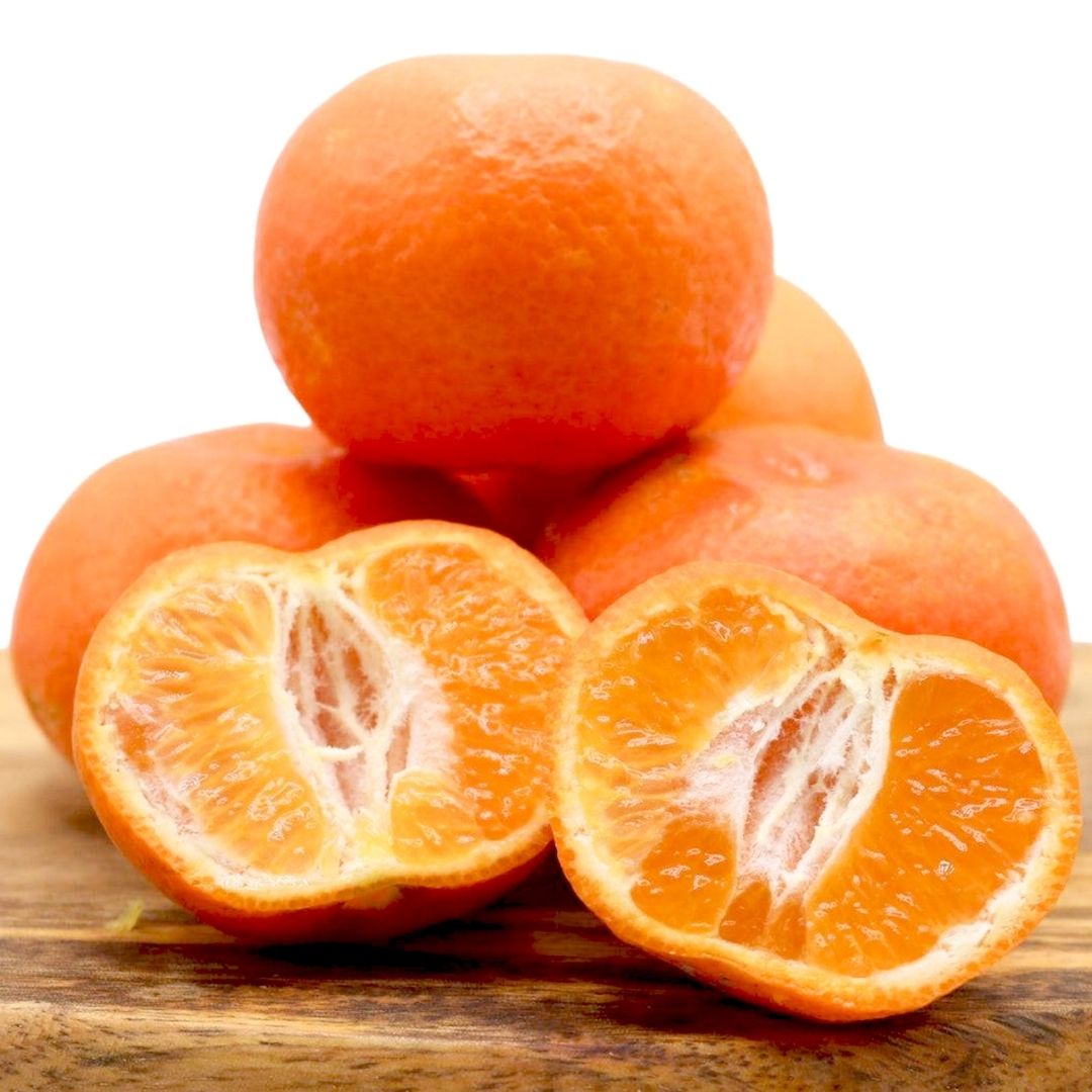 Tangerines on a wooden cutting board with one sliced open, on a white background