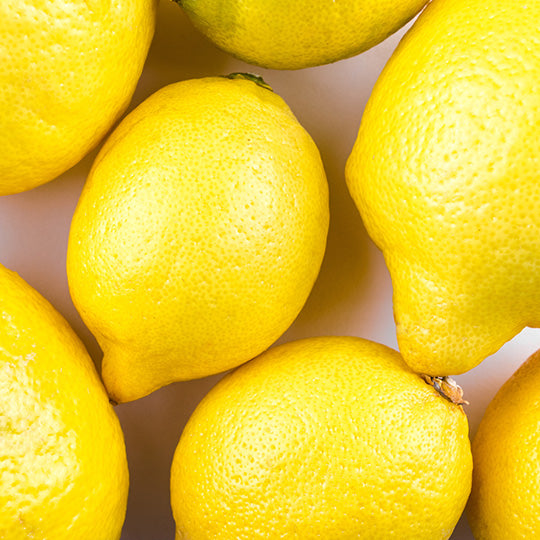 Close-up of several bright yellow lemons on a light background