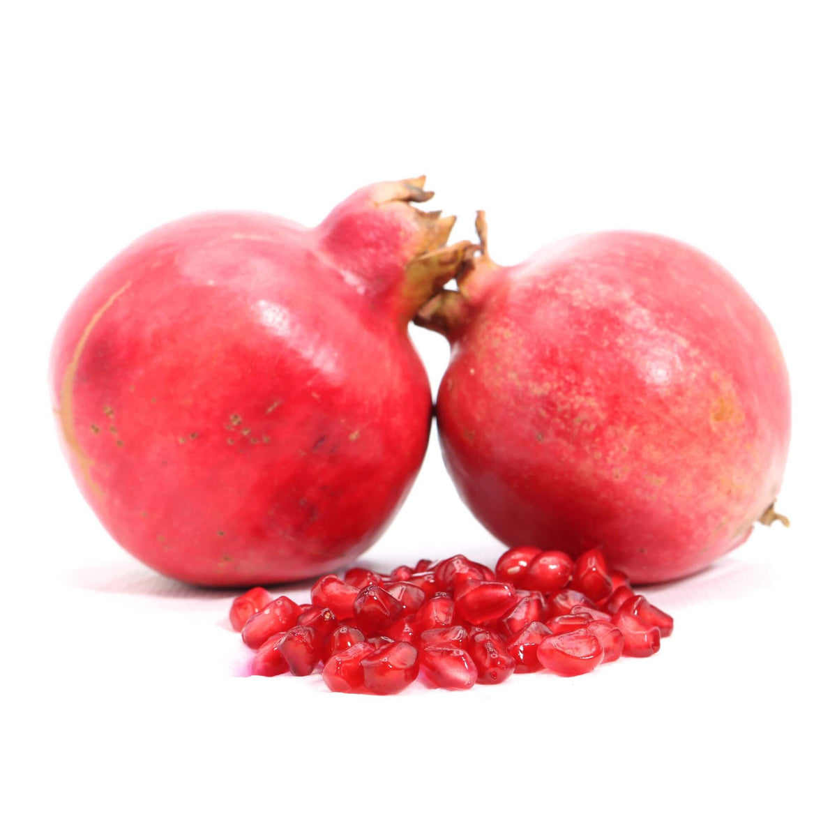 Two whole red pomegranates with a small pile of bright red seeds in front, photographed on a clean white background.