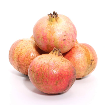 Four whole pomegranates with pinkish-red skin and pale yellow-beige areas, arranged in a small pile on a clean white background.