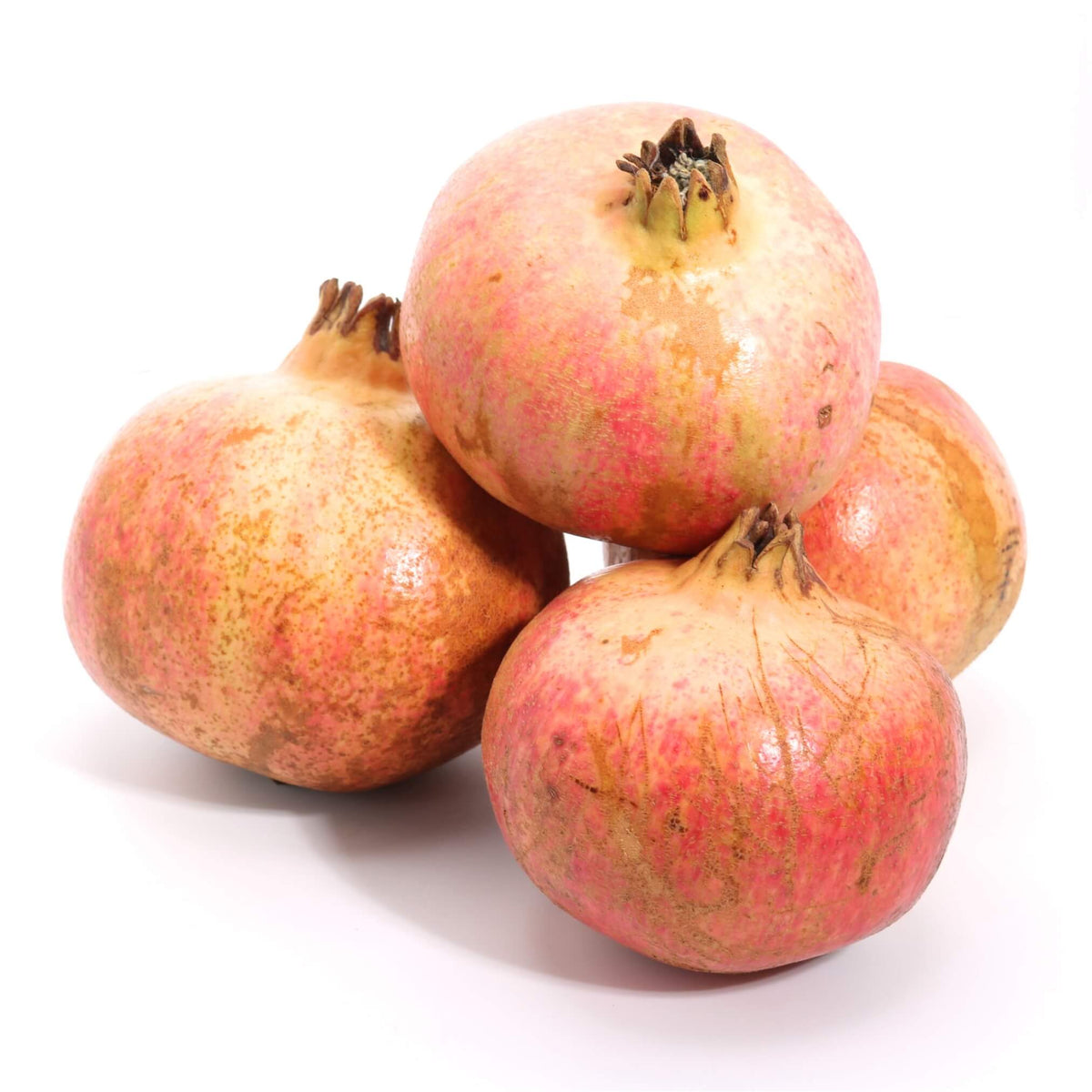 Four whole pomegranates with textured pinkish-red skins and brownish stems, arranged together on a clean white background.