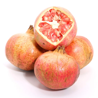 Four pomegranates on a white background, with one cut open to show the red arils inside.